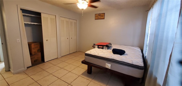 tiled bedroom with two closets and ceiling fan