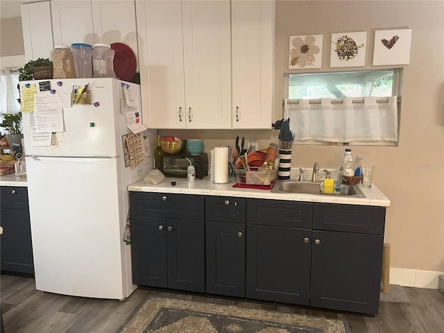 1874 Douglas Ave, Clearwater, FL 33755 - kitchen featuring white cabinetry, wood finished floors, a sink, and freestanding refrigerator