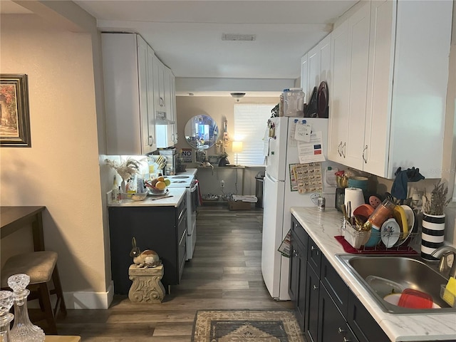 kitchen featuring sink, white appliances, and white cabinetry