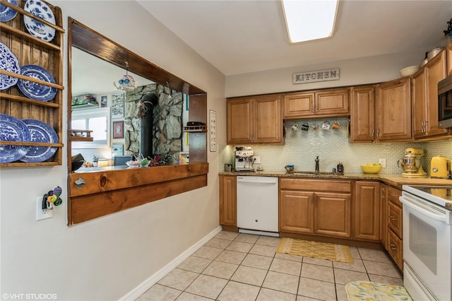 kitchen with white appliances, a wood stove, light tile patterned floors, sink, and light stone counters