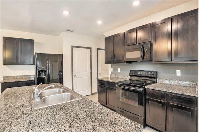 kitchen with black appliances, light stone counters, sink, and dark brown cabinetry