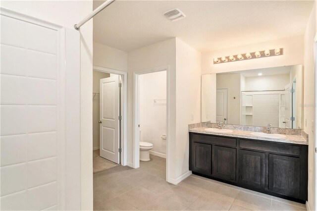 bathroom with vanity, toilet, an enclosed shower, and tile patterned floors