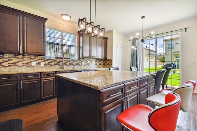 kitchen featuring dark hardwood / wood-style floors, a kitchen island, an inviting chandelier, and hanging light fixtures