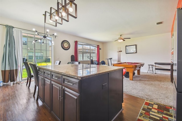 kitchen featuring dark wood-type flooring, decorative light fixtures, a center island, and pool table