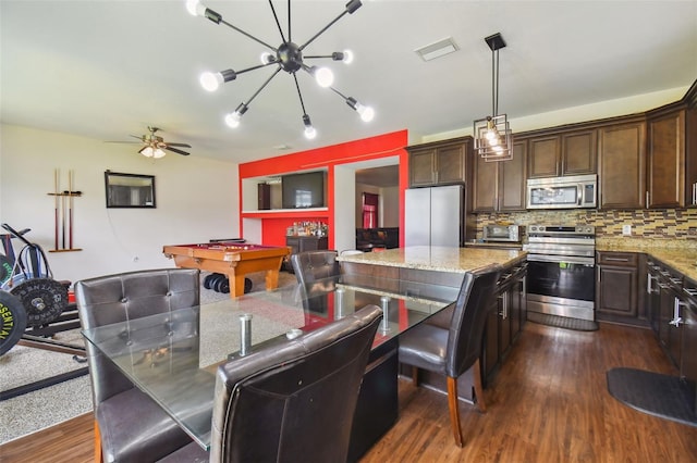 kitchen with ceiling fan with notable chandelier, stainless steel appliances, dark hardwood / wood-style floors, dark brown cabinets, and pendant lighting