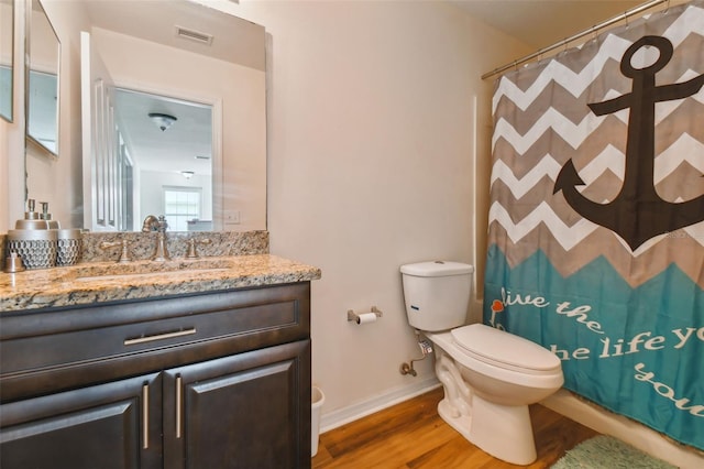 bathroom featuring wood-type flooring, toilet, walk in shower, and vanity