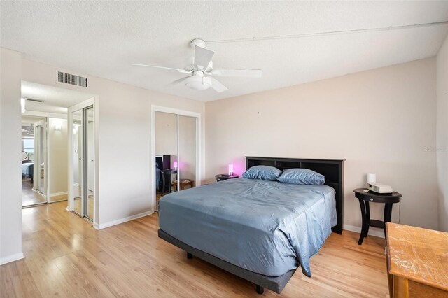 bedroom with a textured ceiling, ceiling fan, and light wood-type flooring