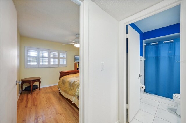 bedroom with a textured ceiling, light hardwood / wood-style flooring, and ceiling fan