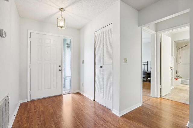 entryway with baseboards, visible vents, and wood finished floors