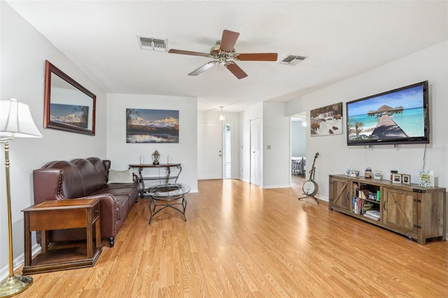 living room with a ceiling fan, wood finished floors, baseboards, and visible vents