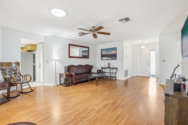 living room with light wood-type flooring, a textured ceiling, and ceiling fan