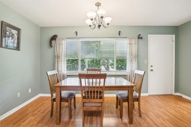 dining room with a notable chandelier, light hardwood / wood-style flooring, and a textured ceiling