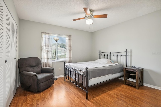 bedroom with ceiling fan, a textured ceiling, a closet, and hardwood / wood-style floors