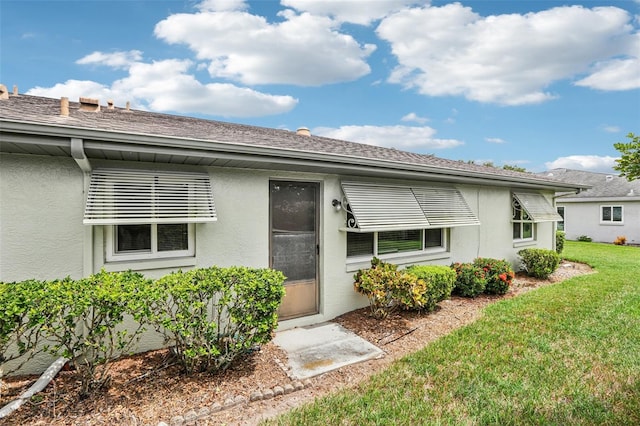 exterior space with stucco siding and a yard