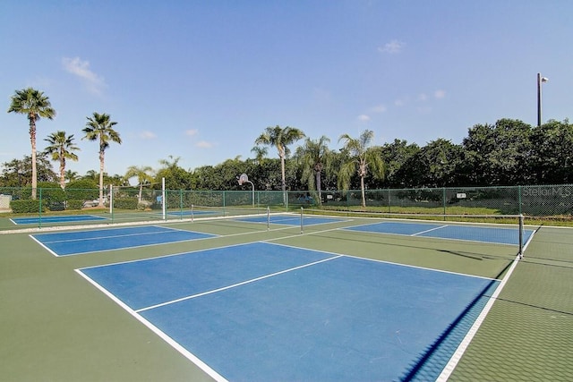 view of tennis court featuring community basketball court and fence