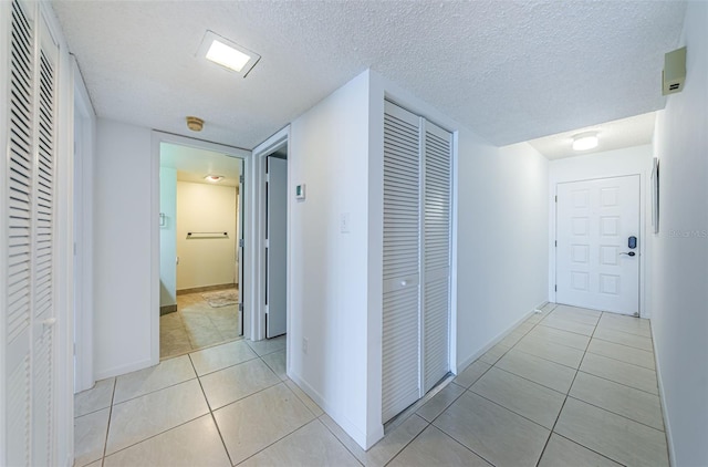 hall with a textured ceiling and light tile patterned flooring