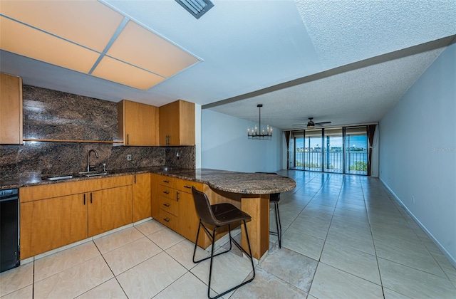 kitchen featuring decorative backsplash, kitchen peninsula, a breakfast bar area, ceiling fan, and sink