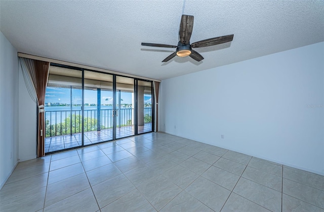7037 Sunset Dr S Unit 602, South Pasadena, FL 33707 - spare room with a wall of windows, ceiling fan, light tile patterned flooring, and a textured ceiling