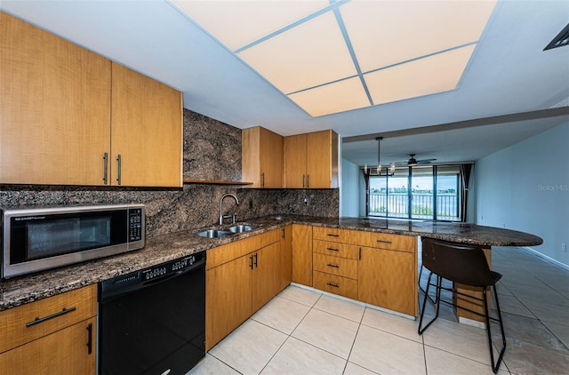 kitchen featuring black dishwasher, sink, kitchen peninsula, a kitchen breakfast bar, and decorative backsplash