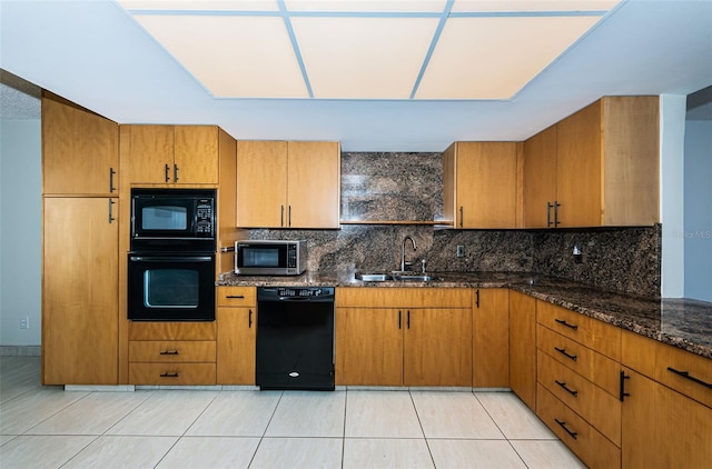 kitchen featuring black appliances, dark stone countertops, decorative backsplash, and sink