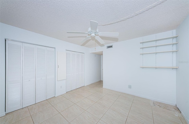 unfurnished bedroom with ceiling fan, multiple closets, a textured ceiling, and light tile patterned flooring