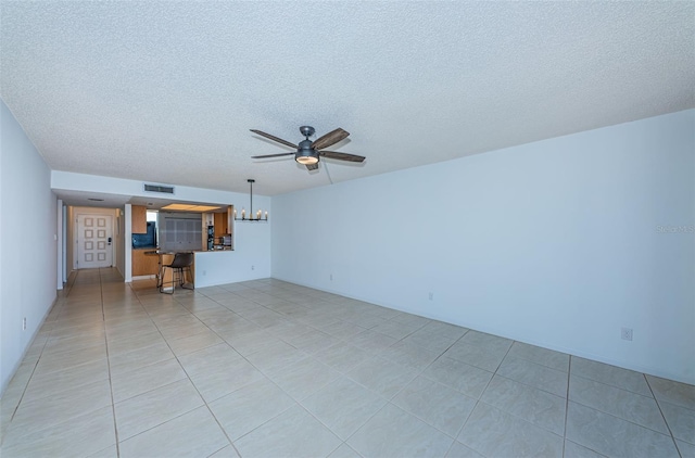 unfurnished living room with ceiling fan with notable chandelier, a textured ceiling, and light tile patterned floors