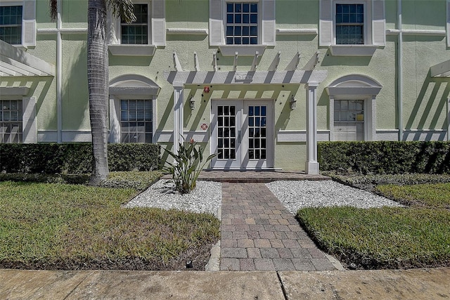 view of exterior entry featuring french doors and a pergola