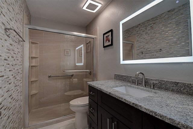 bathroom with vanity, toilet, an enclosed shower, and a textured ceiling