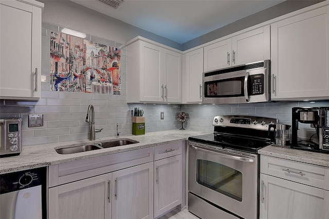 kitchen with light stone counters, stainless steel appliances, sink, and tasteful backsplash