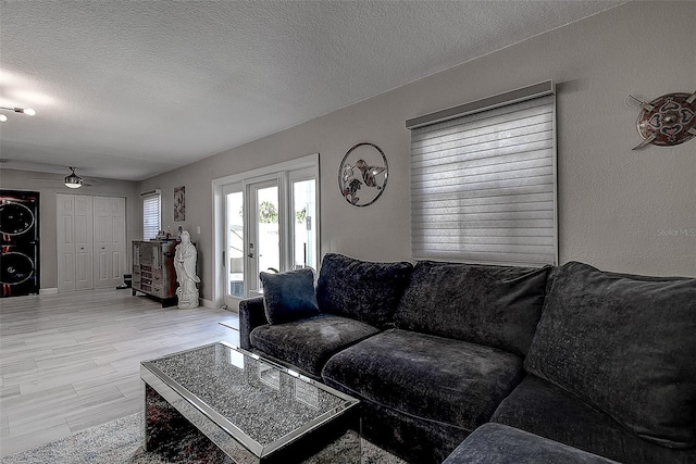 living room featuring a textured ceiling, light hardwood / wood-style flooring, and ceiling fan