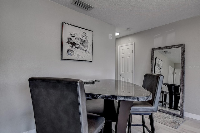 dining space featuring light wood-type flooring and a textured ceiling