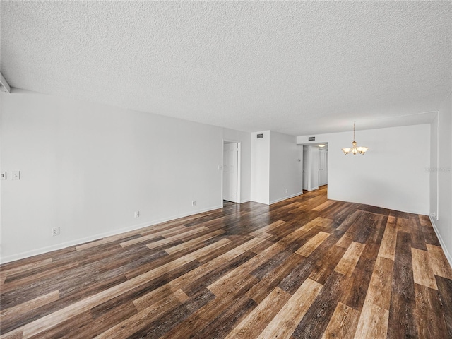 unfurnished living room featuring dark hardwood / wood-style flooring, a notable chandelier, and a textured ceiling