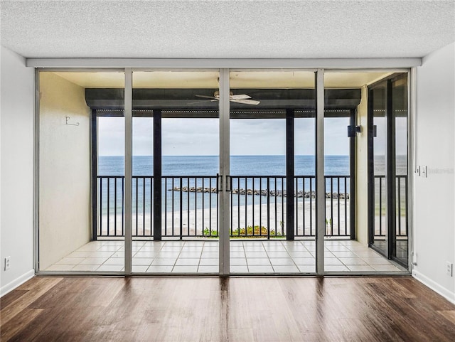 unfurnished sunroom featuring a wealth of natural light, a view of the beach, and a water view