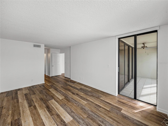 spare room featuring dark wood-type flooring, a textured ceiling, and ceiling fan