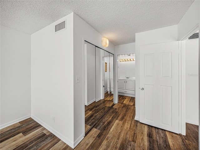 7100 Sunset Way Unit 405, St Pete Beach, FL 33706 - interior space featuring a textured ceiling, dark wood-type flooring, a closet, and baseboards