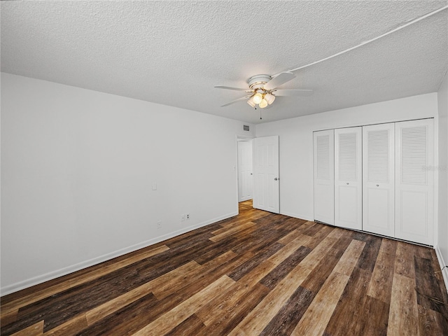 unfurnished bedroom with a textured ceiling, dark wood-type flooring, ceiling fan, and a closet