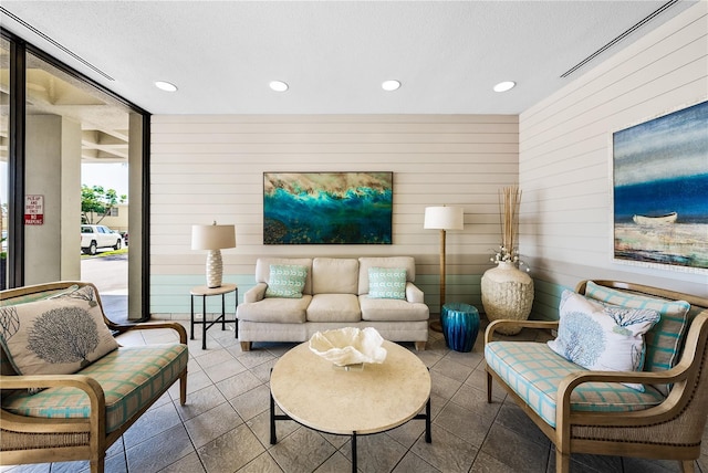 living room featuring a textured ceiling and wooden walls