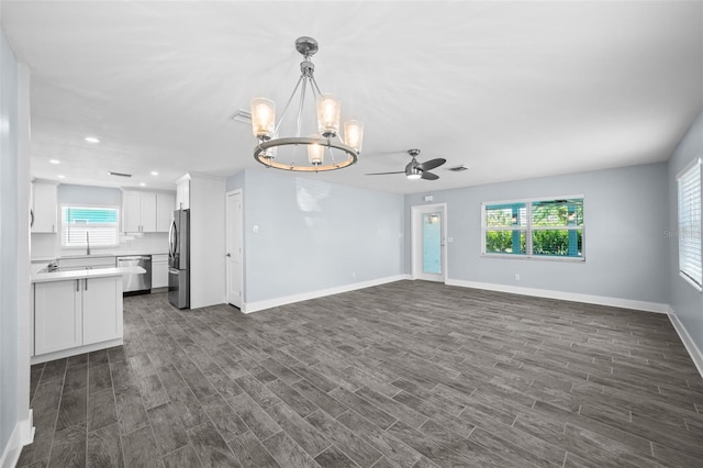 unfurnished living room with ceiling fan with notable chandelier and dark hardwood / wood-style flooring