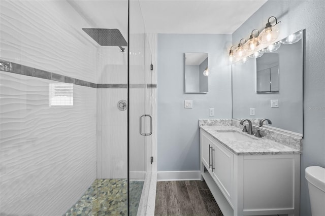 bathroom featuring vanity, hardwood / wood-style floors, a shower with shower door, and toilet