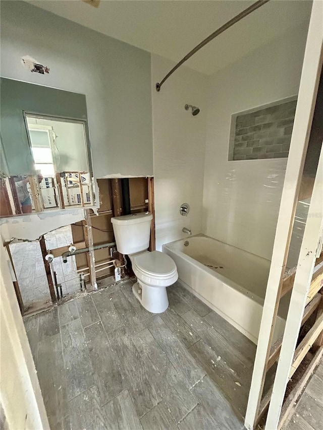 bathroom with toilet and tiled shower / bath