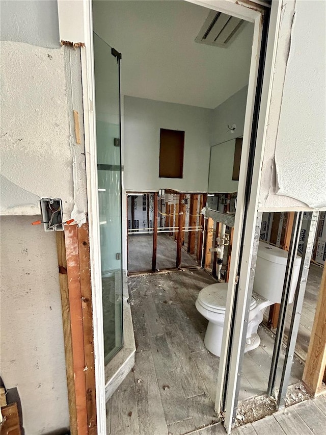 bathroom with toilet, an enclosed shower, and hardwood / wood-style floors