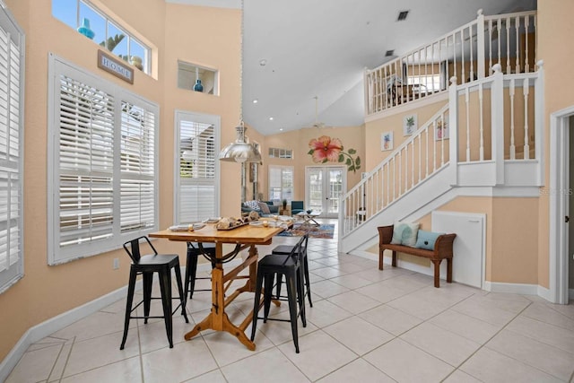 dining space with high vaulted ceiling and light tile patterned floors