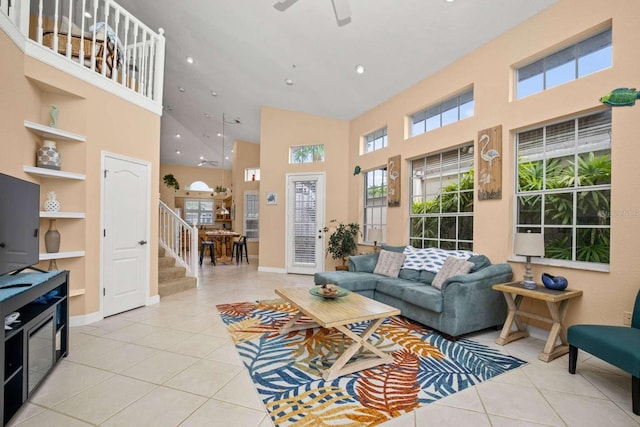 tiled living room with ceiling fan and high vaulted ceiling