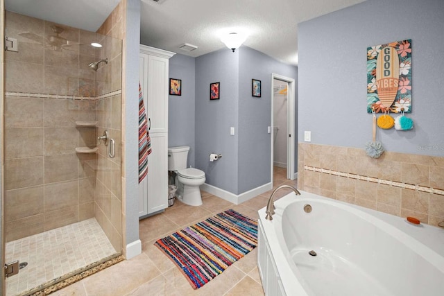 bathroom featuring plus walk in shower, tile patterned flooring, toilet, and a textured ceiling