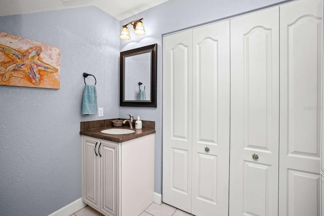 bathroom with tile patterned floors, vaulted ceiling, and vanity