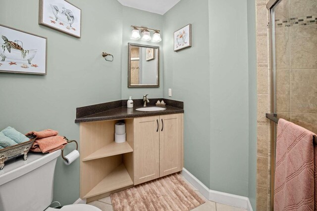 bathroom featuring a stall shower, baseboards, toilet, tile patterned floors, and vanity