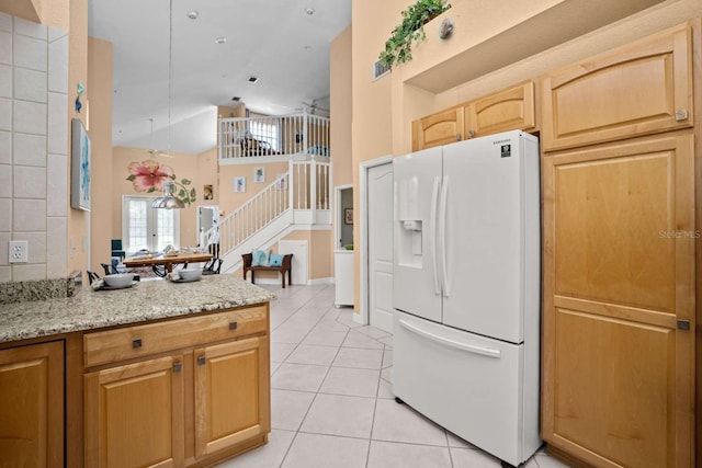 kitchen featuring light tile patterned floors, light stone countertops, ceiling fan, and white refrigerator with ice dispenser