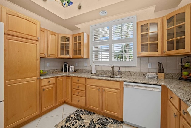 kitchen featuring light tile patterned floors, light stone counters, white dishwasher, sink, and decorative backsplash