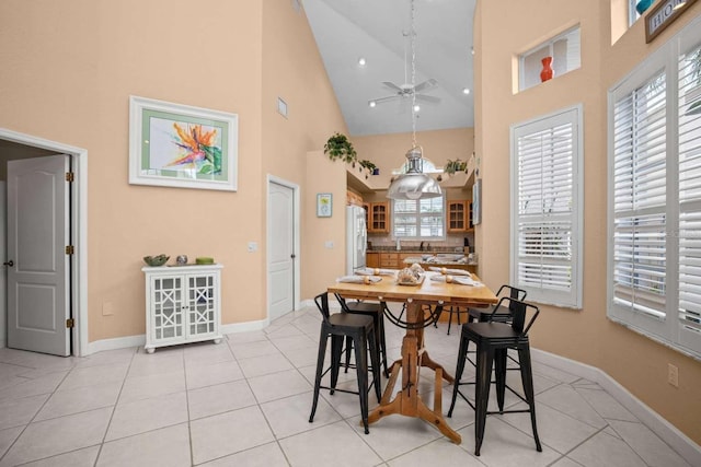 tiled dining room with ceiling fan and high vaulted ceiling