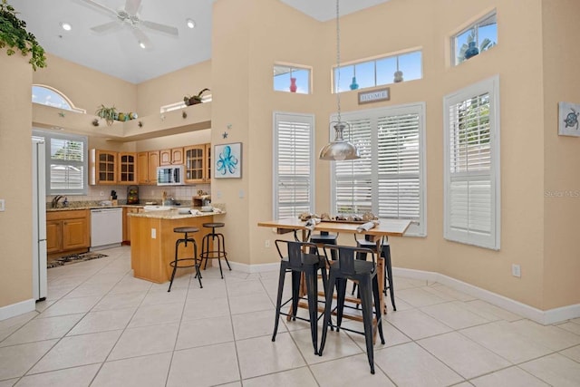 dining area with a healthy amount of sunlight, light tile patterned flooring, a high ceiling, and ceiling fan